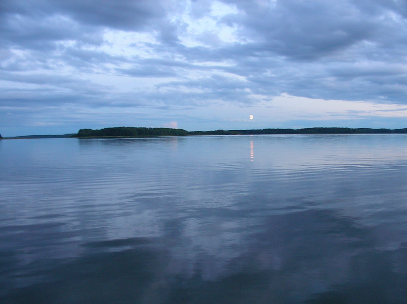 Sommarkväll med måne som spelar sig i sjön Mälaren.