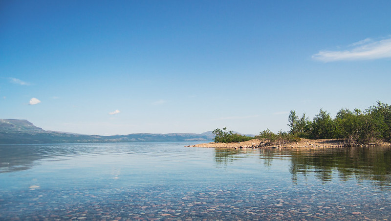 Klart vatten i Torneträsk sjön med berg i bakgrunden. 