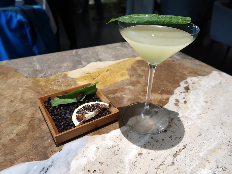 Liten trälåda innehållande peppar, citron och blad, bredvid står ett martiniglas med drink i.