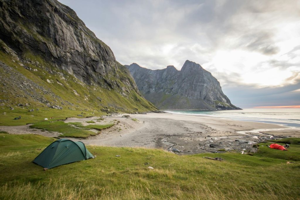 Uppslagna tält vid en strand på Lofoten med berg runt omkring